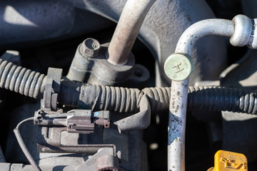 Car wiring, hoses and air conditioning duct. Dusty details of a flat-four (boxer) car engine compartment under the open hood. Closeup view on a sunny day