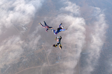 Skydiving. Three skydivers are in the sky above white clouds.