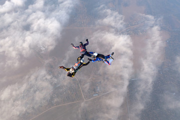 Naklejka na ściany i meble Skydiving. Three skydivers are in the sky above white clouds.