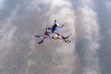 Skydiving. Three skydivers are in the sky above white clouds.