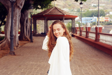 A girl in a white cape walks along the Icod de los Vinos. A girl in a white dress walks. Summer, sport, hiking, walk, Canary. Icod de los Vinos Spain