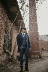 A man posing in the image of an English retro gangster dressed in Peaky blinders style near...