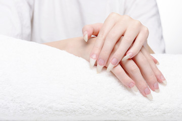 Obraz na płótnie Canvas Beautiful hands of young woman close-up on towel. Spa treatments for nails. Space for text. Woman holds hands on towel for manicure treatment procedure in spa salon.