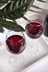 Two glasses with red grape wine with bottle on the background. Romantic dinner concept.