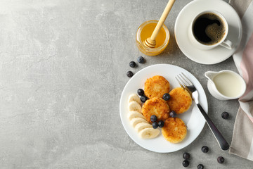 Breakfast of cheese pancakes on grey background, top view