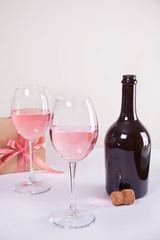 Two glasses with pink grape wine, gift box and bottle on the background. Romantic dinner concept.