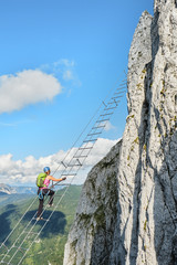 Woman on via ferrata Intersport Klettersteig in Donnerkogel mountains, Austria.