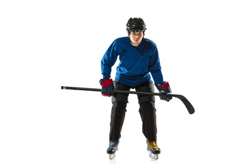 Young female hockey player with the stick on ice court and white background. Sportswoman wearing equipment and helmet training. Concept of sport, healthy lifestyle, motion, action, human emotions.