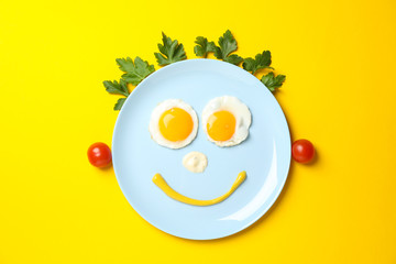 Smile face made of plate with fried eggs on yellow background, top view