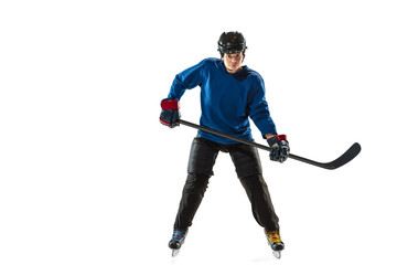 Fototapeta na wymiar Young female hockey player with the stick on ice court and white background. Sportswoman wearing equipment and helmet training. Concept of sport, healthy lifestyle, motion, action, human emotions.