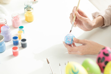 A woman holding a brush to paint an easter egg for cerebration