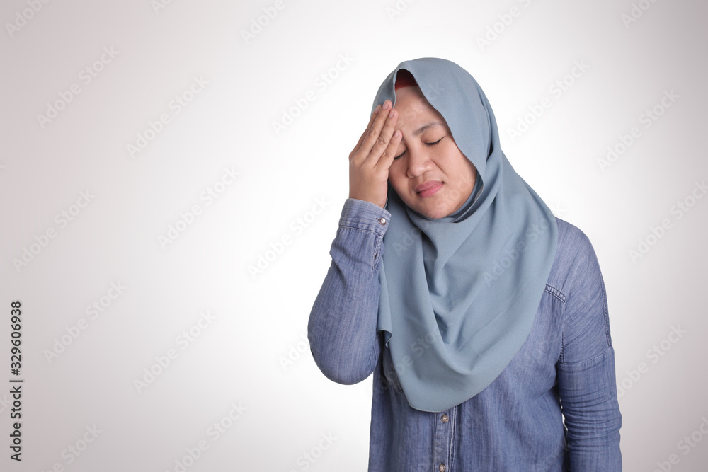 Wall mural Portrait of Asian muslim lady wearing hijab hold her head in pain for having headache