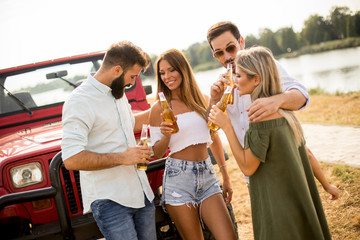 Obraz premium Group of young people drinking and having fun by car outdoor