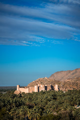 Fototapeta na wymiar Sunset view of the Nakhal Fort surrounded by a palm grove, Oman