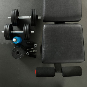 Gym interior and flat photo of bench with dumbbells. 