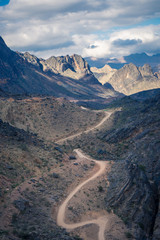 View of the dirt road between mountains on a cloudy day in Jebel Shams, Oman