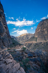 View of the dirt road between mountains on a cloudy day in Jebel Shams, Oman