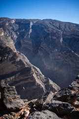 Fototapeta na wymiar Sunrise with small clouds ascending in the Grand Canyon of Jebel Shams, Oman
