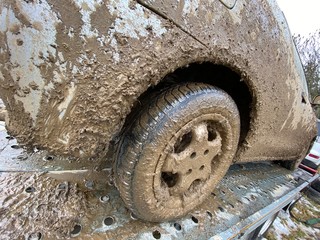 The detail of the car completely dirty by mud after the drag race on a field during winter. It needs complete cleaning of the exterior and interior. 