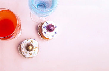 Sweet, colorful cupcakes decorated with sugar paste and cream with two glass of sweet water. Concept of art paty. Flat lay, top veiw.