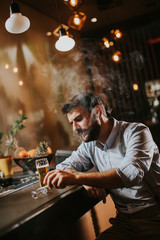 Man drinking beer and smoking cigarette at pub