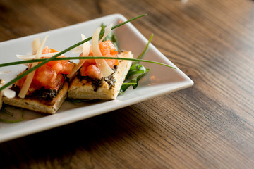 Bruschetta with olive and garlic pesto, with cherry tomato and parmesan leaves