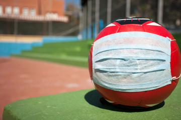 coronavirus soccer concept, ball with mask on soccer field, school