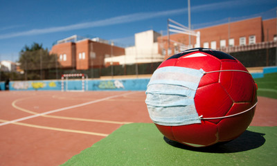 coronavirus soccer concept, ball with mask on soccer field, school