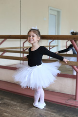 Fototapeta premium vertical portrait of a smiling little ballerina at the ballet machine