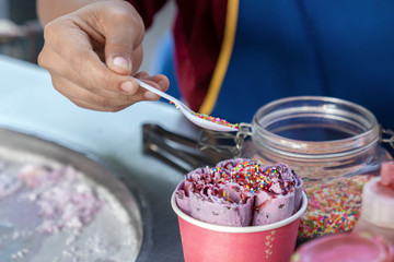 the preparation of ice-cream , Thai street food, cook sprinkles ice cream in a paper Cup with caramel