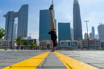 Acrobat keep balance one the hands with blurred Dubai cityscape. Concept of modern, business and unlimited possibility 