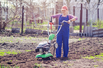 Young girl plows the land with a cultivator in spring garden
