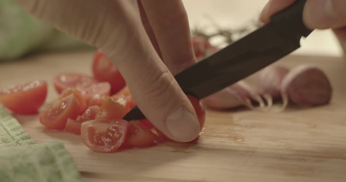 Tagliare i pomodori su un tagliere di legno