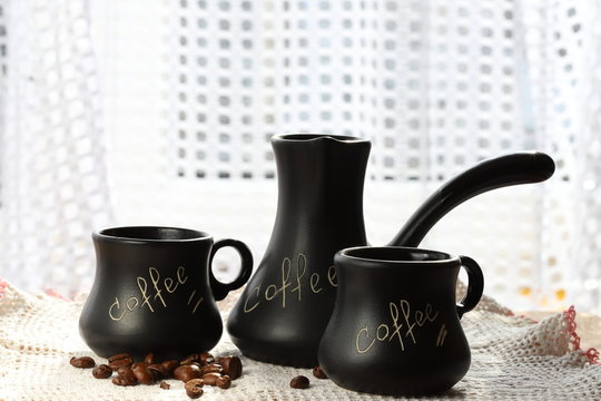 Керамічний набір чорної кави, чашки та індички з написом "кава", кавових зерен, в білому середовищі. Білий фон. Смачна кава концепції.
