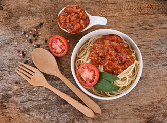 Pasta with tomato sauce and basil on wooden background