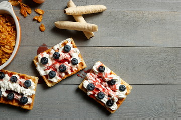 Belgian Waffle with cream, blueberries and strawberry syrup on the top 