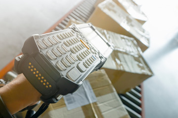 Warehouse worker is scanning barcode scanner on package boxes on conveyor belt, packaging boxes, delivering shipment goods
