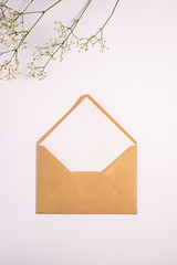 Kraft brown paper envelope with white empty card, gypsophila flowers, white background, mockup...