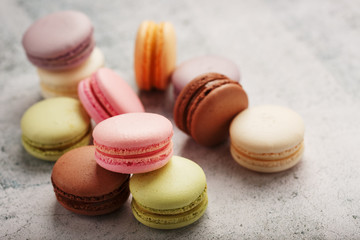 Multicolored macaroni cookies lie on a gray stone slab.