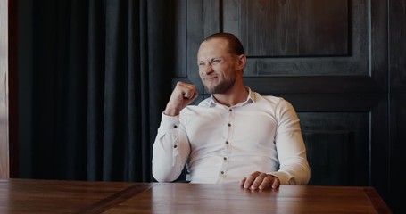 Pensive adult entrepreneur searching for solution and then rejoicing in success while working in dark modern office