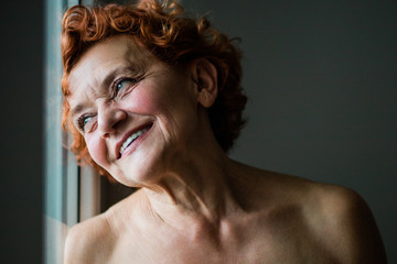 Happy mature woman smiling by the window