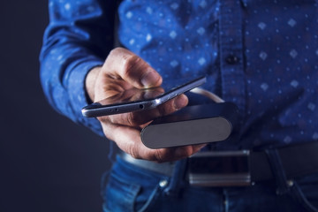 man holds phone and external battery