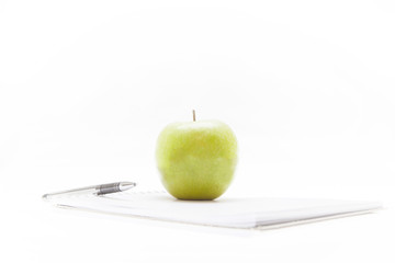 Blank notepad, pen and green apple