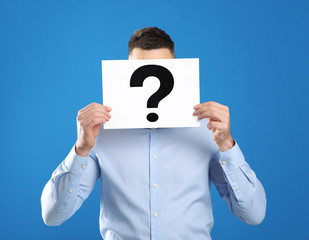 Man holding paper with question mark on blue background