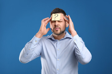 Emotional man with question mark on blue background