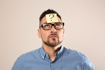 Fototapeta premium Man in eyeglasses with question mark on grey background