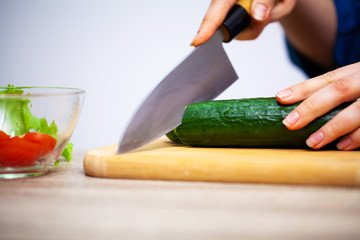 Concept of healthy eating, woman cuts fresh vegetables for salad