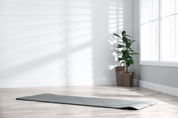 Unrolled grey yoga mat on floor in room