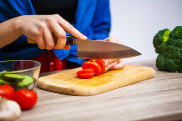 Concept of healthy eating, woman cuts fresh vegetables for salad