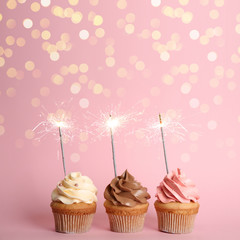 Birthday cupcakes with sparklers on pink background